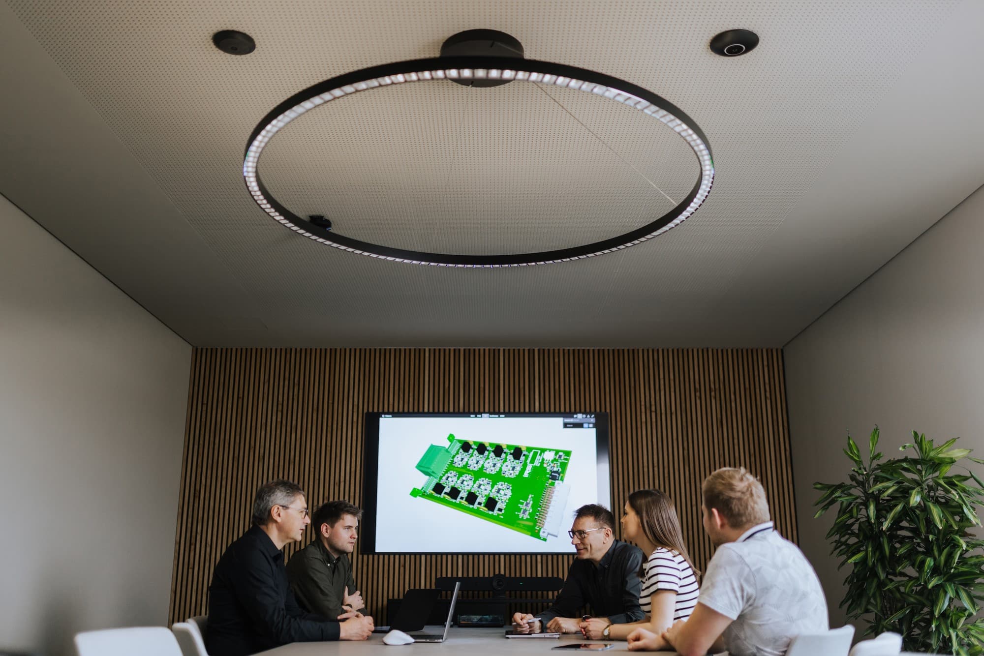 Projektteam bespricht eine Leiterplatte im Besprechungsraum